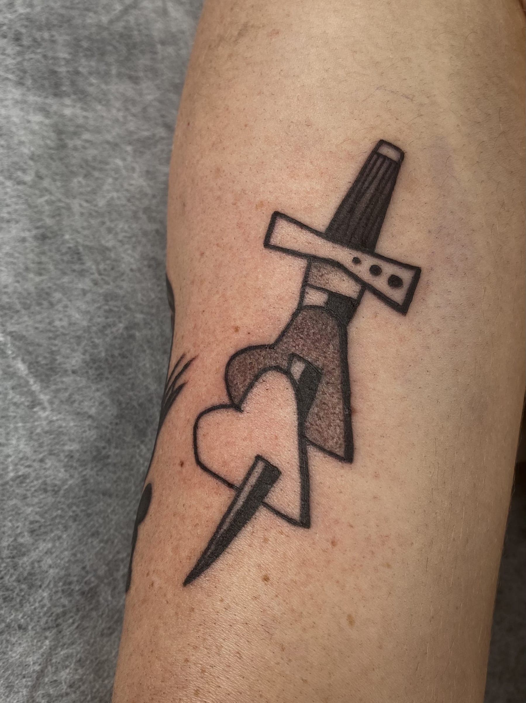 Black traditional dagger through a heart tattoo