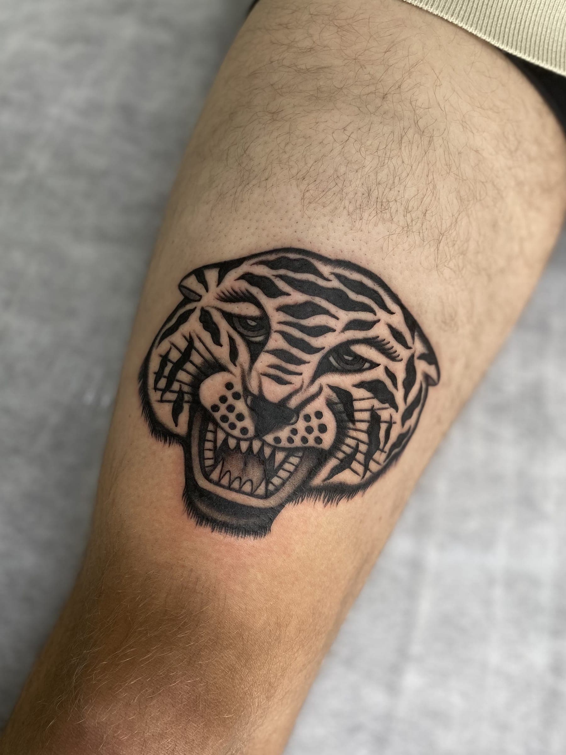 Black traditional roaring tiger head tattoo with bared teeth