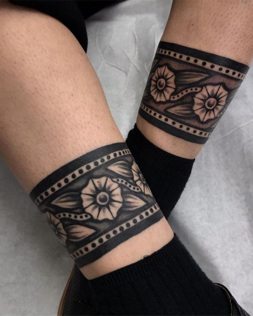 Black and grey traditional floral cuff bands wrapped around both with dotwork borders