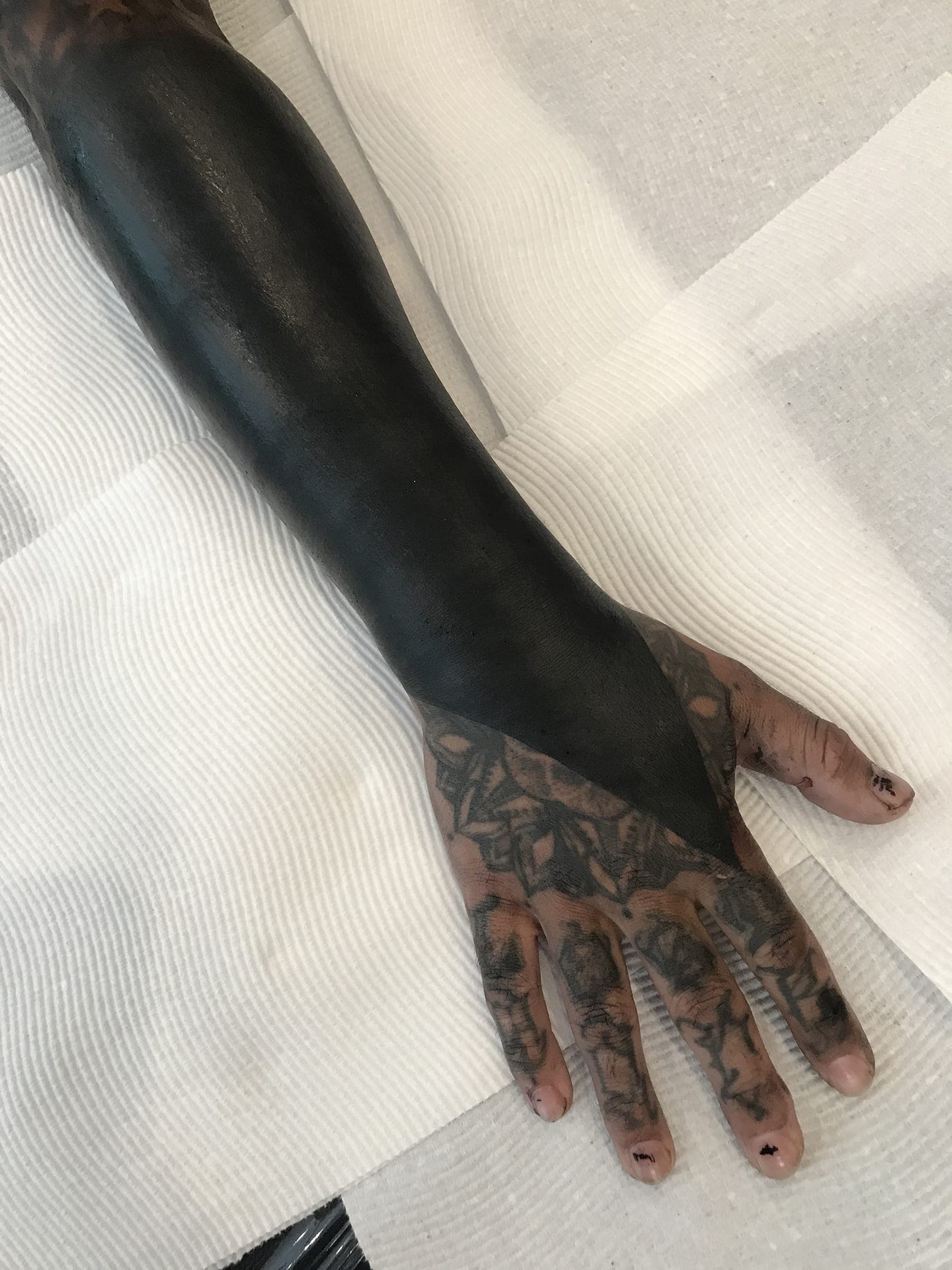 Freshly tattooed solid black meeting an existing finely tattooed at
