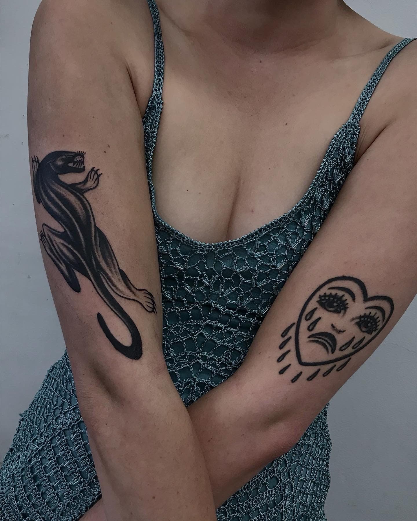 Black and grey traditional crawling panther on the back of the upper arm, head turned mid-snarl