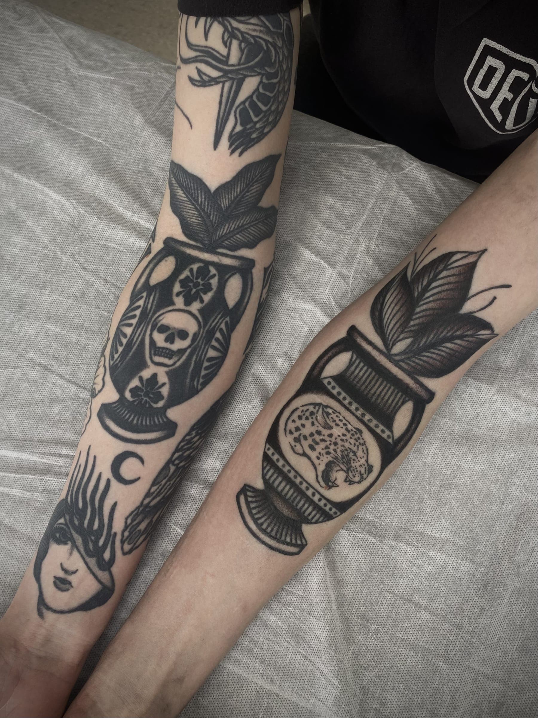 Two matching black urn tattoos with snake and leopard motifs