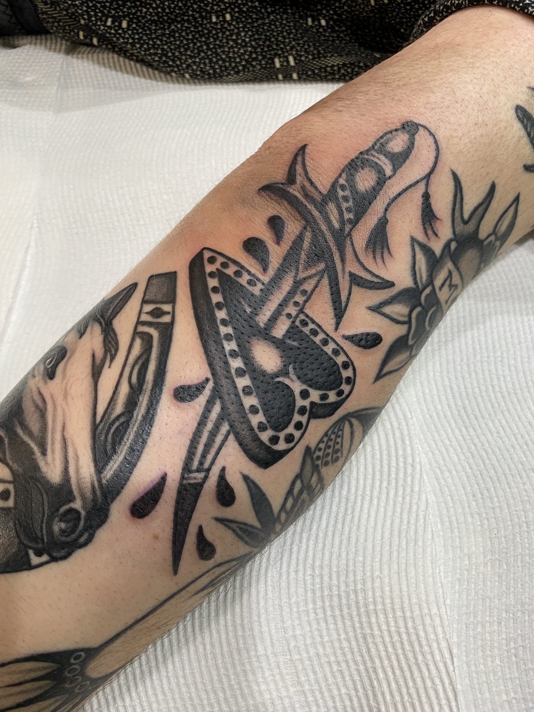 Traditional black horseshoe tattoo pierced by a dotted dagger with a horse head beside it