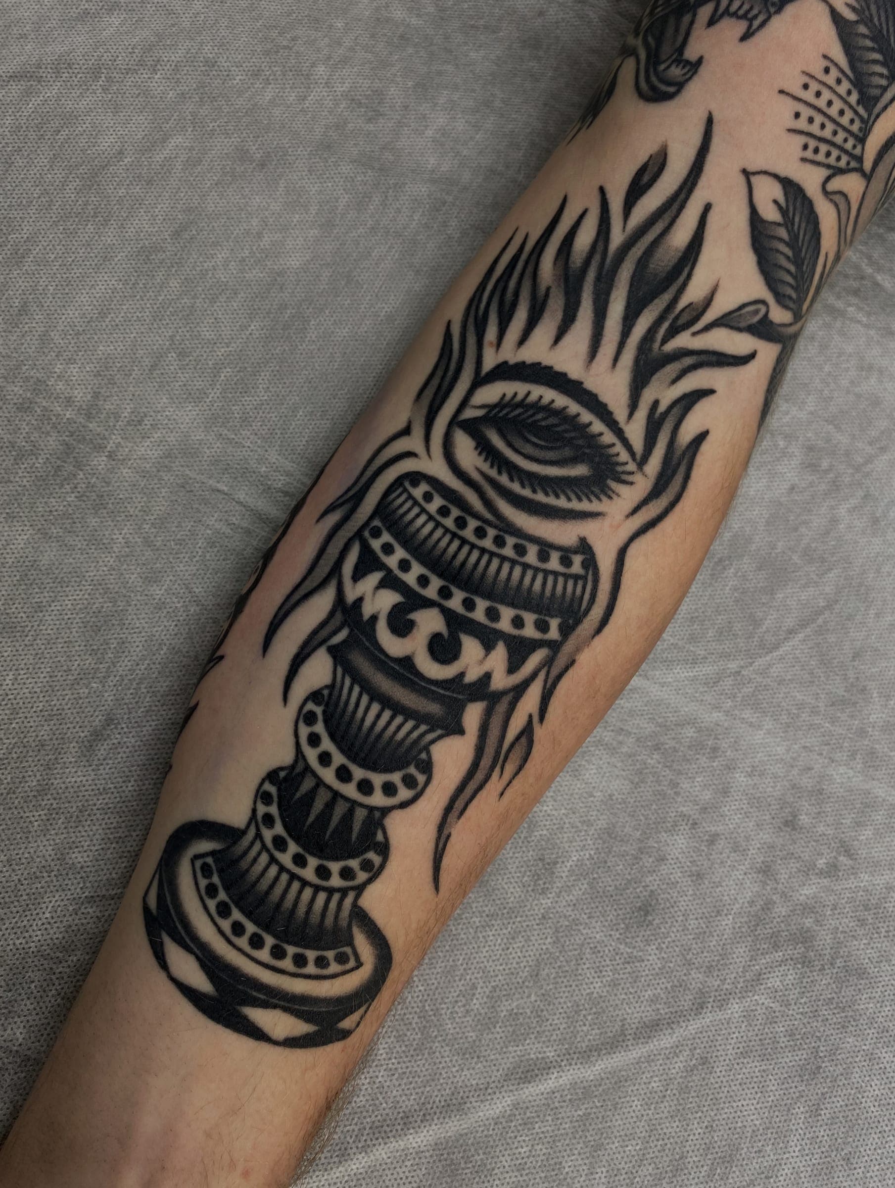 Black traditional flaming torch tattoo with a single eye on inner