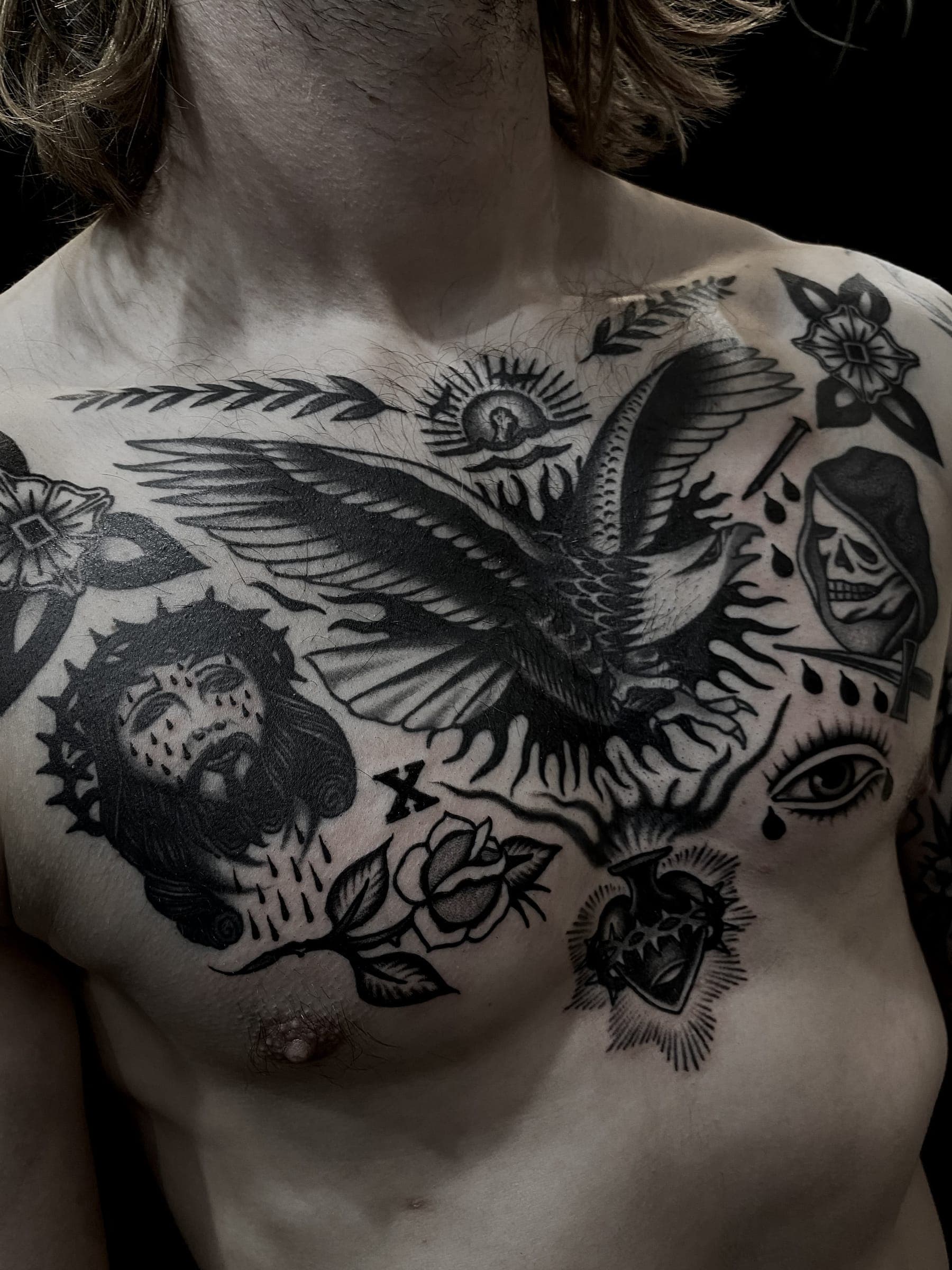 Traditional black tattoo with a spread-wing eagle, head of Christ, weeping eye, skull and sacred heart