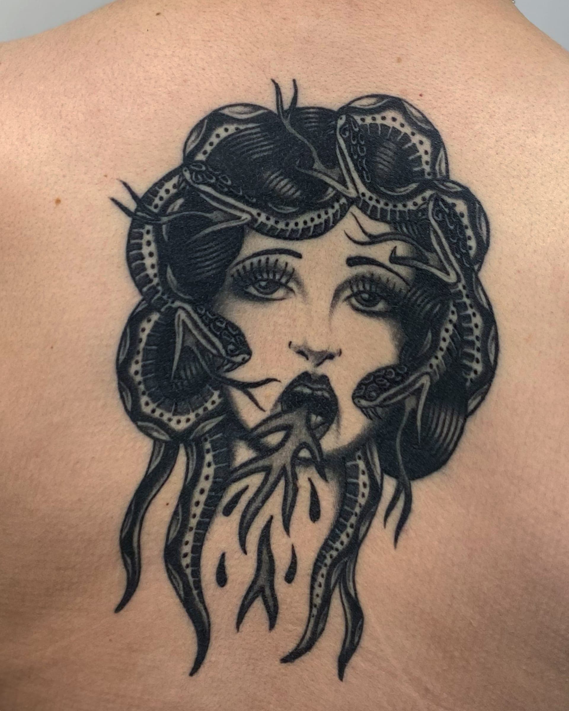 Traditional Medusa face with snakes coiled through her hair and flames spilling from her mouth on the back