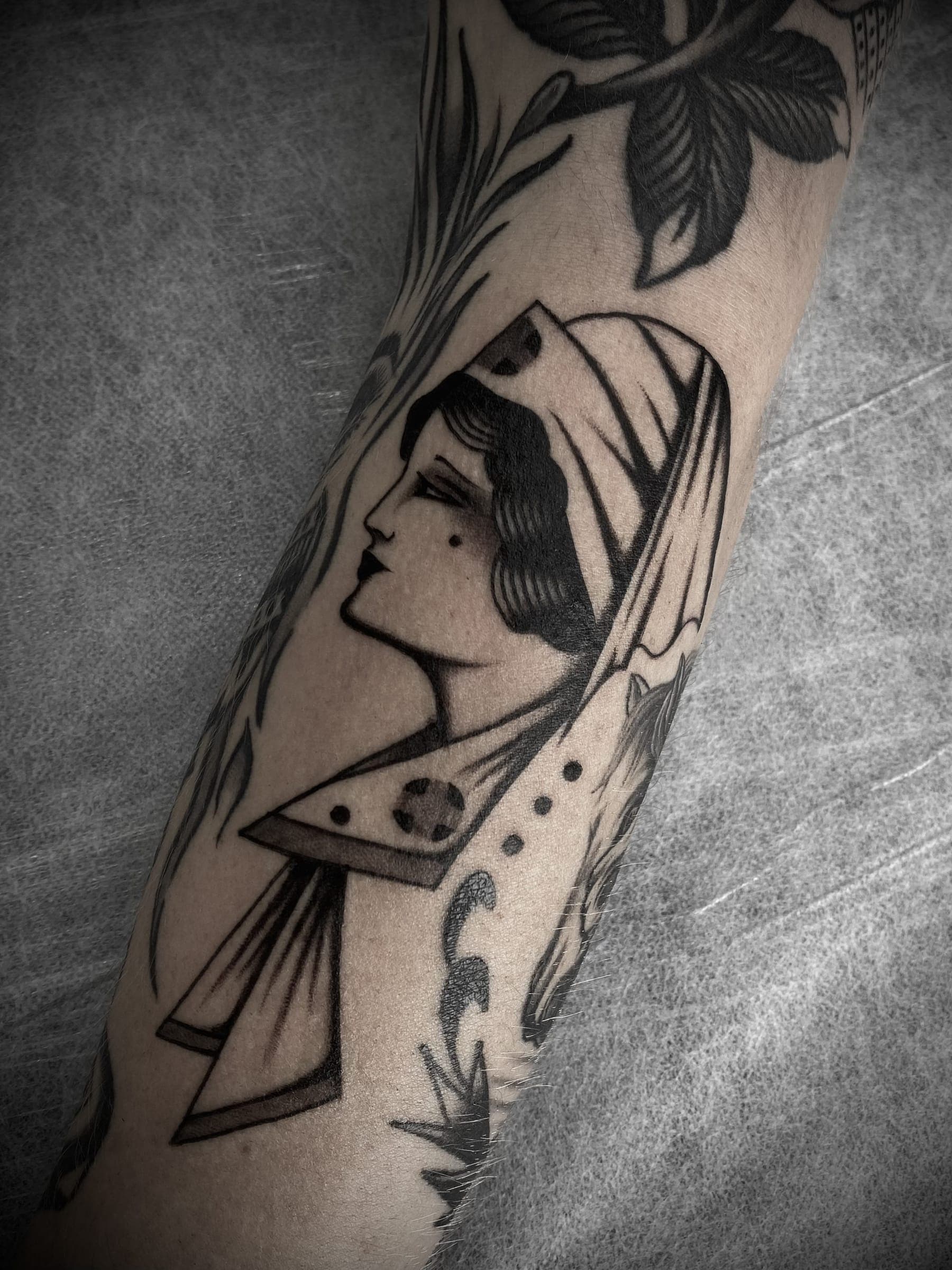 Traditional black lady head tattoo in profile with a draped veil and pointed collar