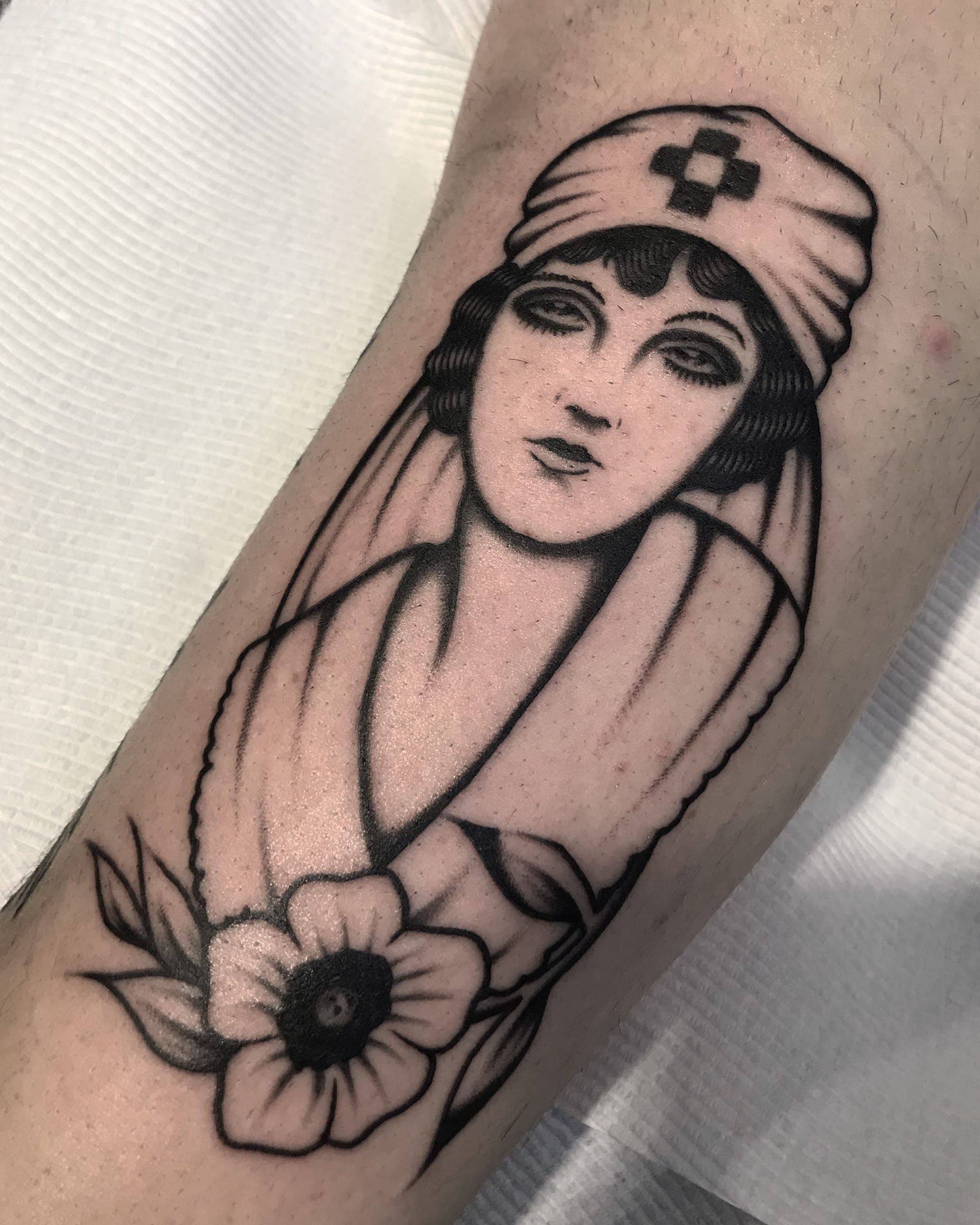 Traditional nurse lady head with a red-cross cap and a single anemone on the forearm