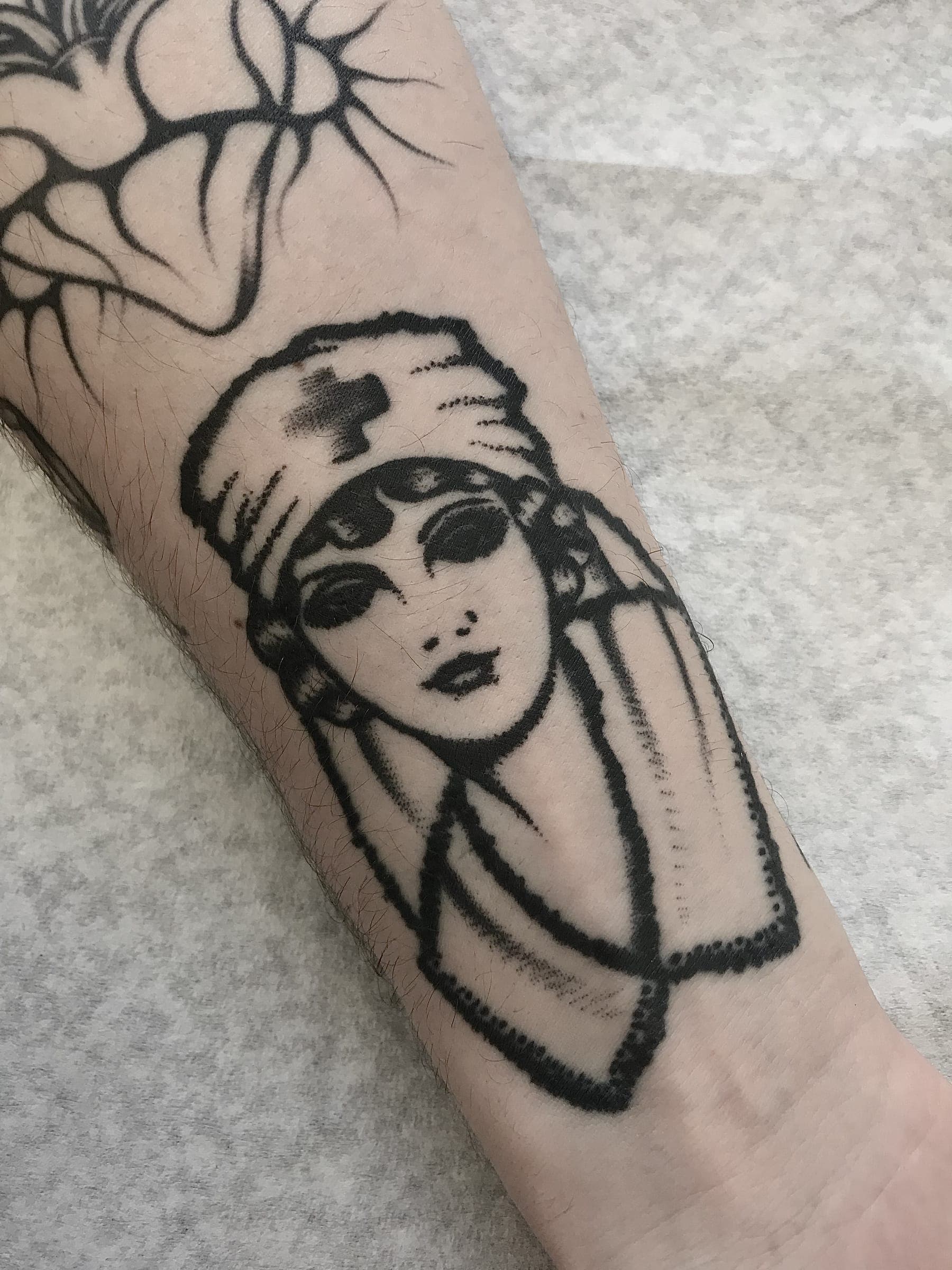 Bold black line traditional nurse lady head with red-cross cap and beaded collar on the forearm
