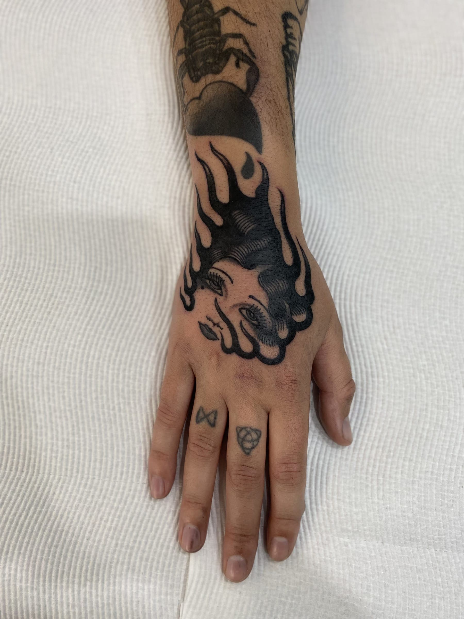 Traditional black lady head tattoo wrapped in curling flames on the back of below a scorpion piece