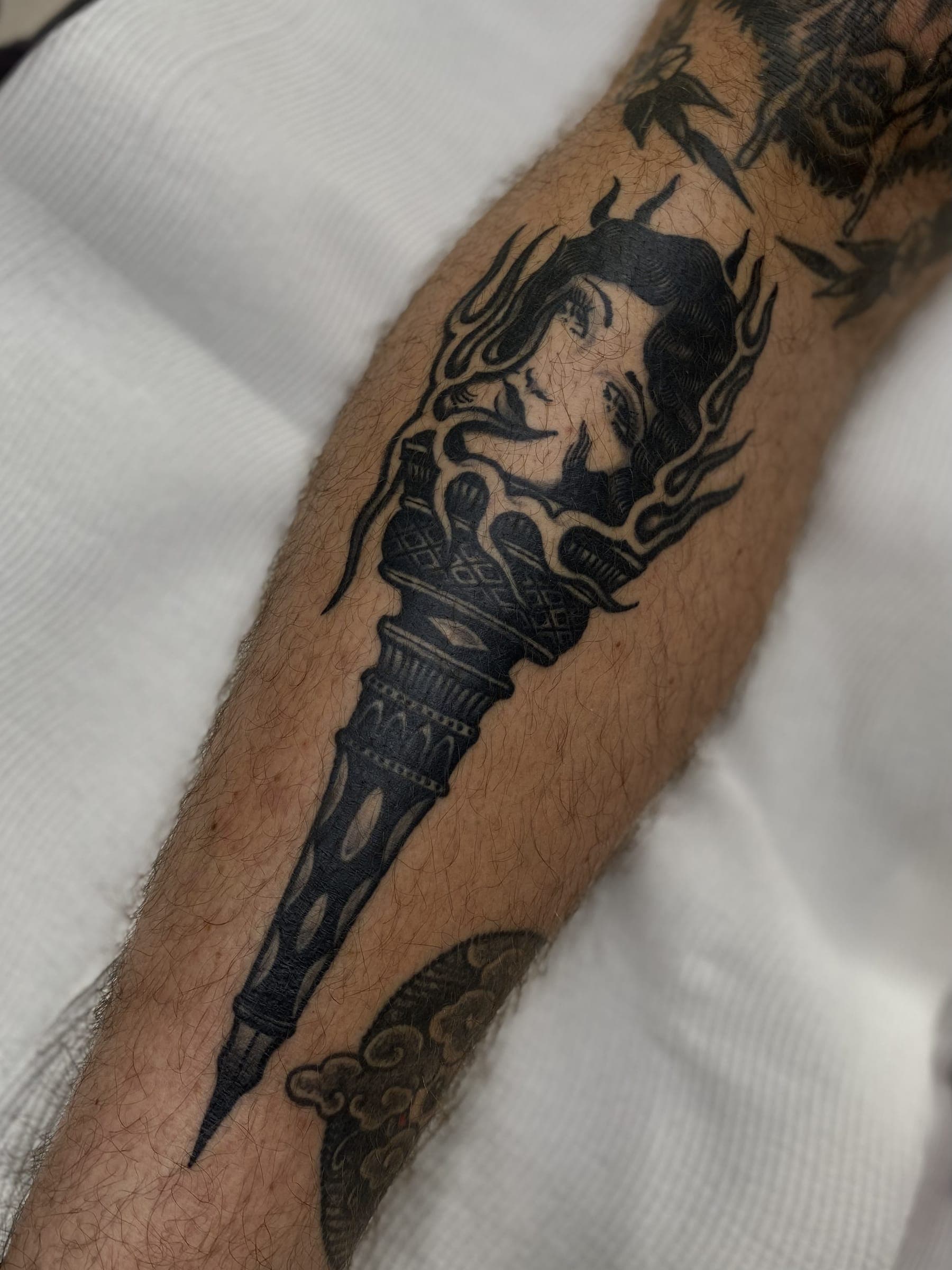 Traditional flaming torch tattoo with a lady's face emerging from the flames