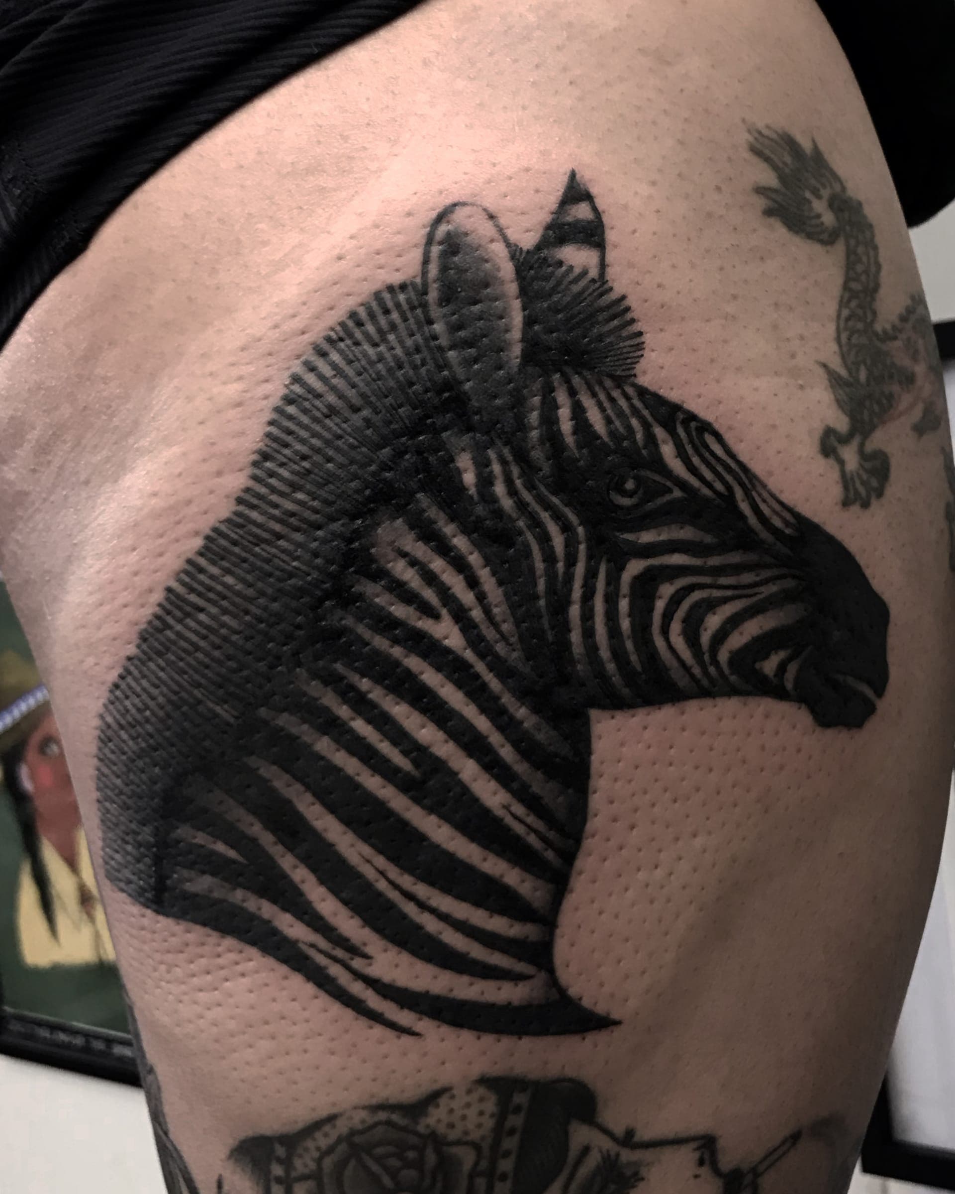 Black ink zebra head in profile with stripes left in negative space on the thigh