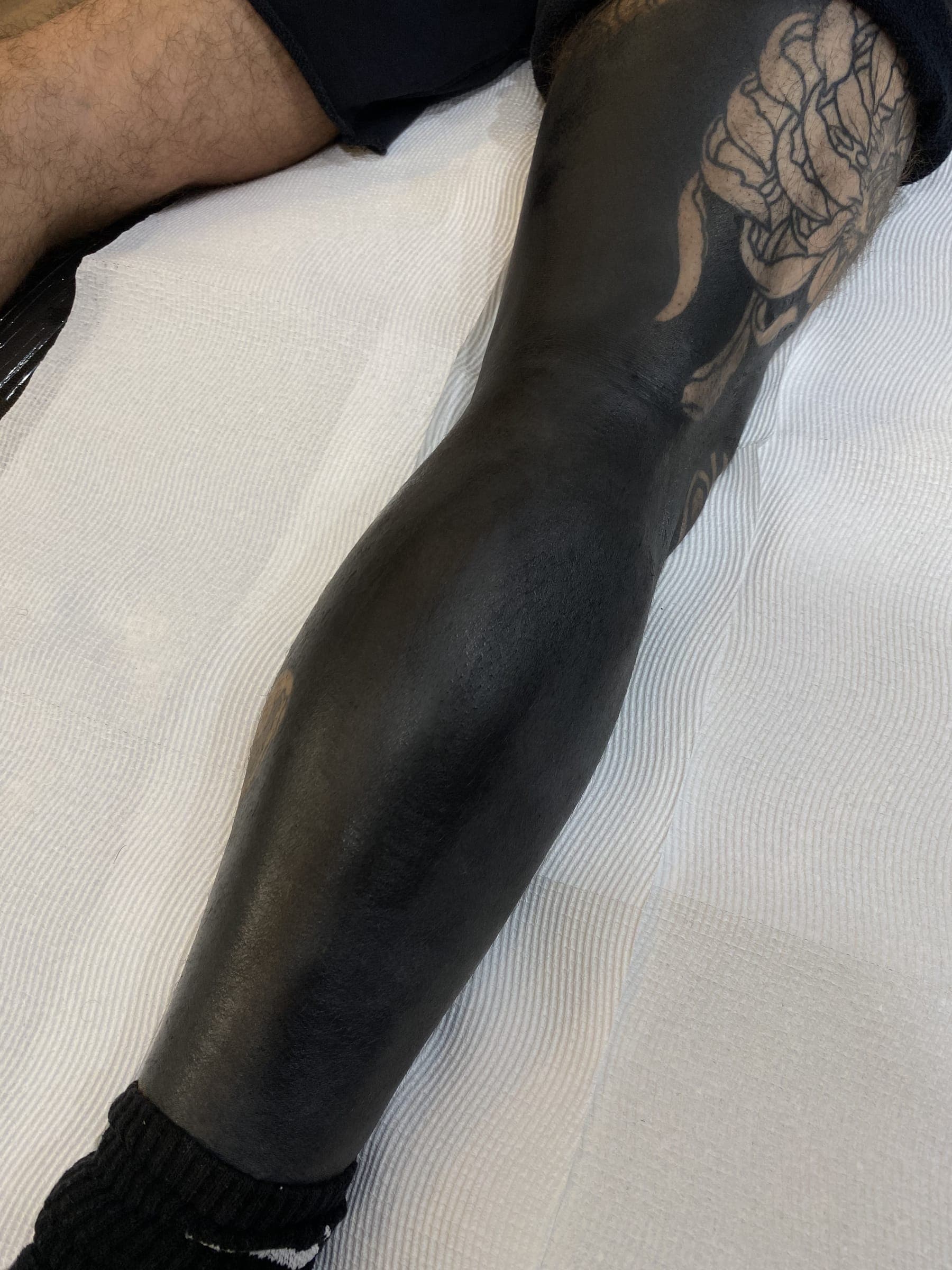 Solid black tattoo running from down to the sock with a faint skull showing