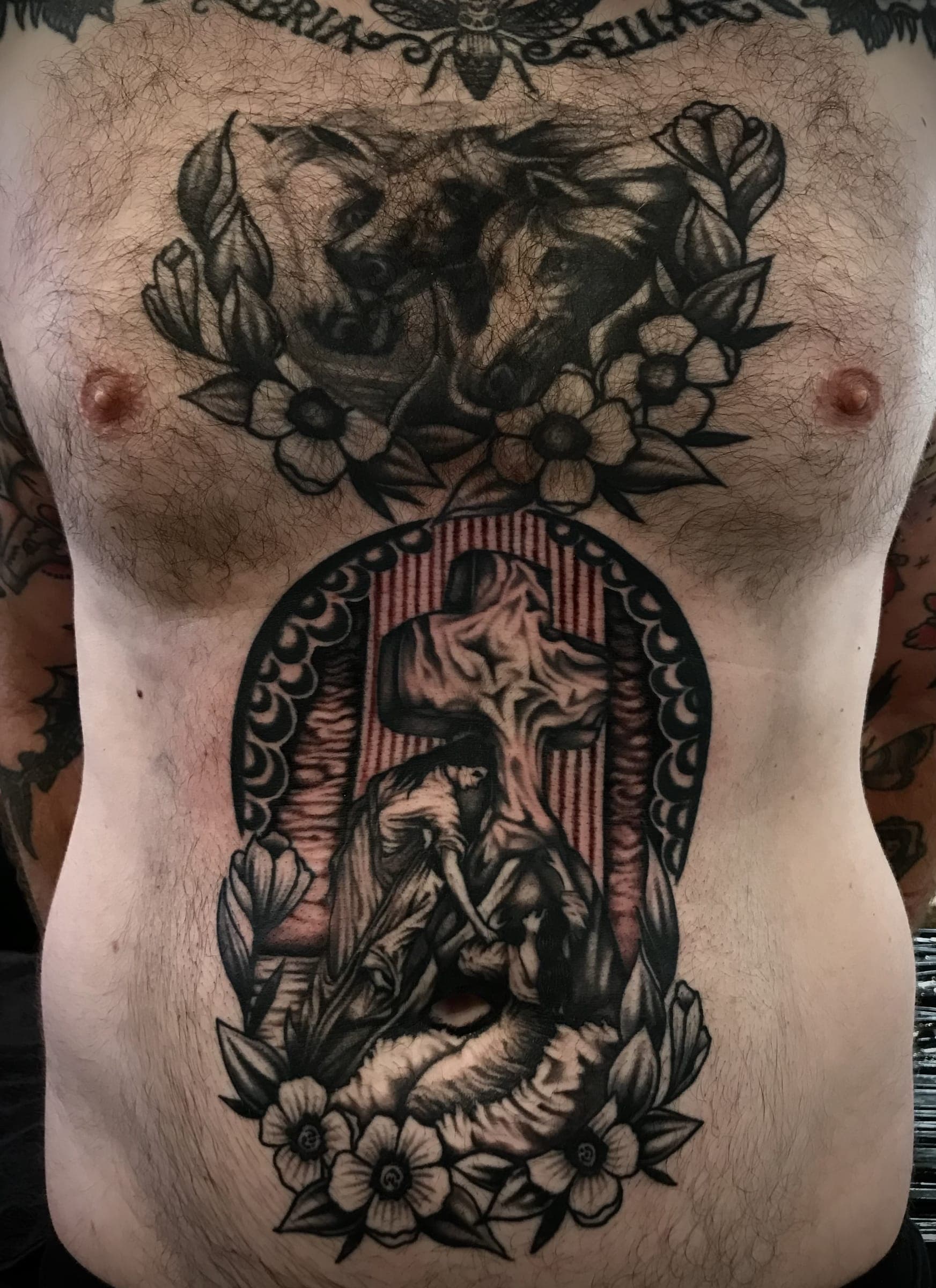 Two wolf heads tattooed above a framed Jesus on the cross
