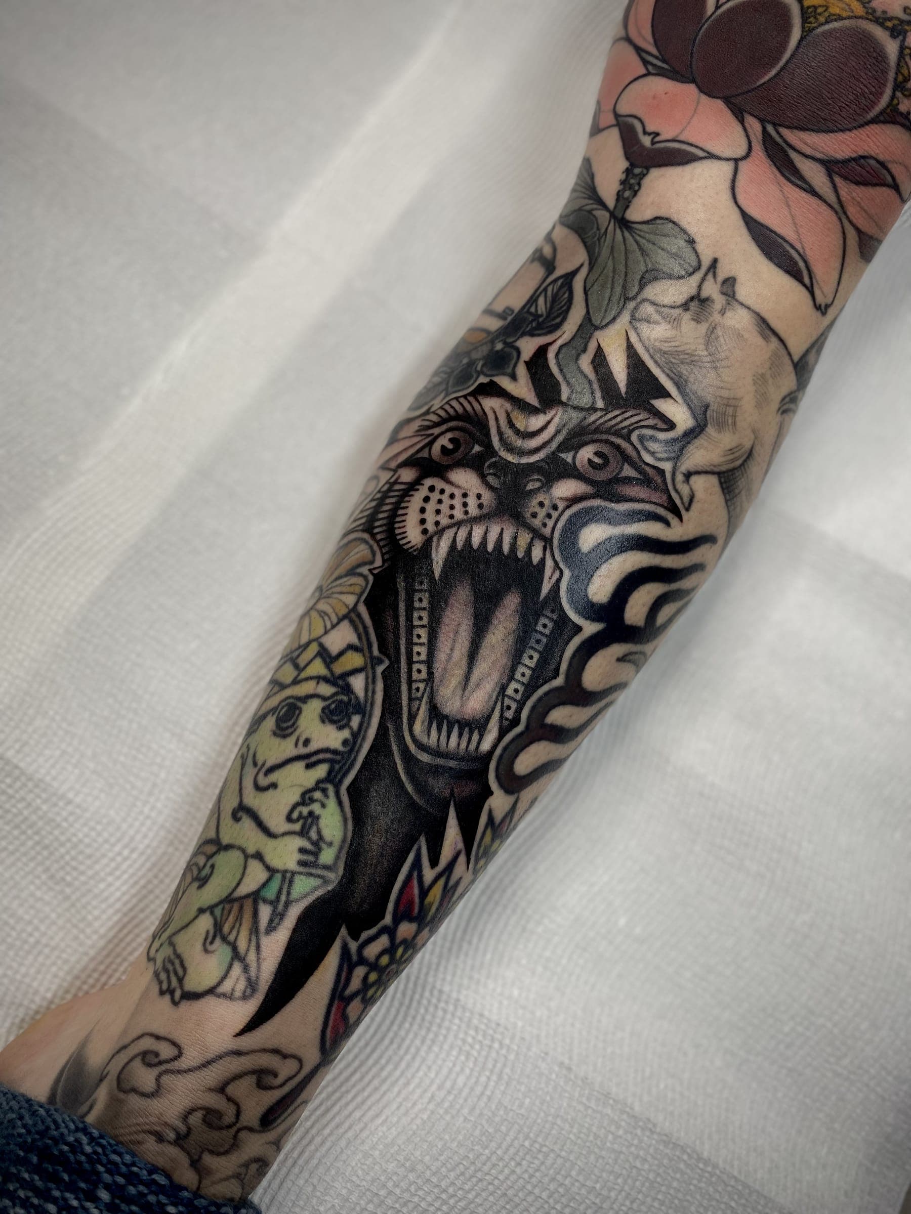 Colour full coverage tattoo with a roaring tiger, frog, lotus flowers and a goat