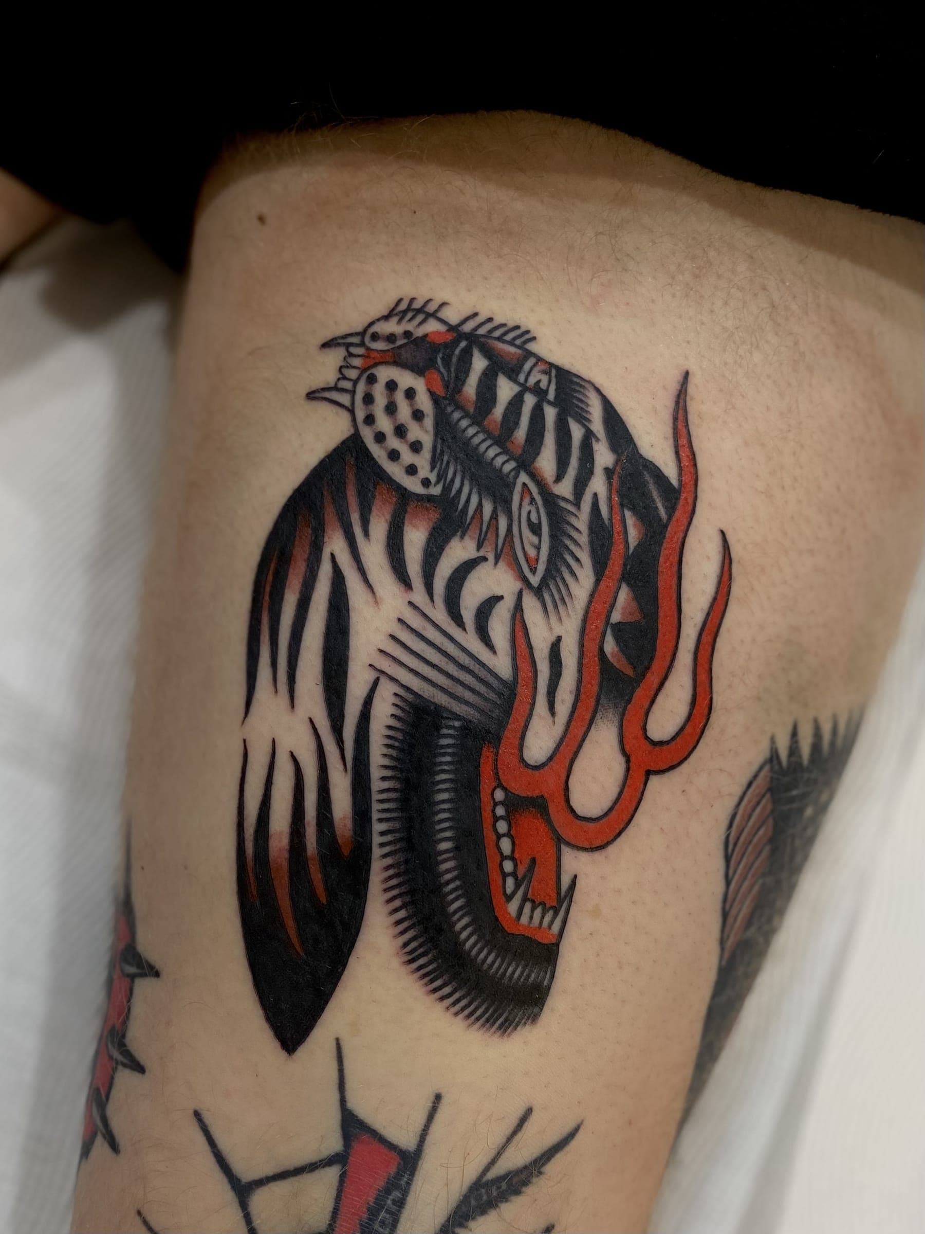Black panther head tattoo with bright red flames and tongue